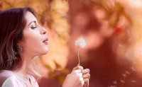 Woman blowing dandelion seeds